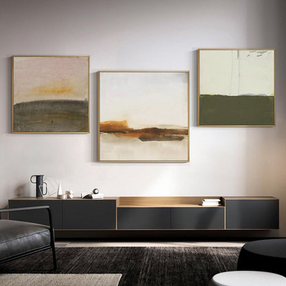 May include: Three abstract landscape paintings in gold frames, hung on a white wall above a black entertainment center with a wooden top.