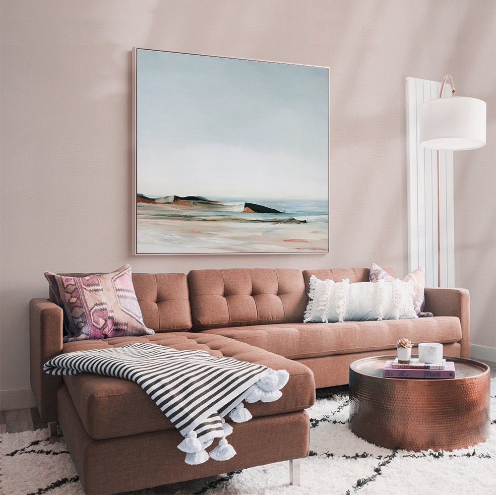 May include: A brown sectional sofa with a white and black striped throw blanket and white pom-poms. The sofa is in a living room with a copper coffee table and a white lamp.
