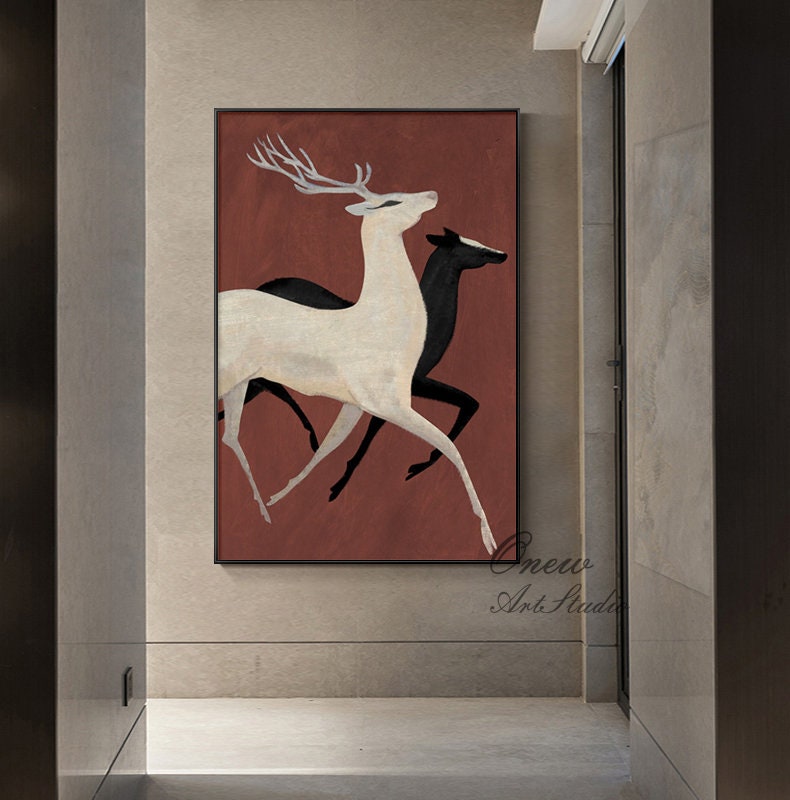 May include: Abstract painting of three white and black deer running on a red background. The deer are stylized and have long legs and antlers. The painting is framed in black.