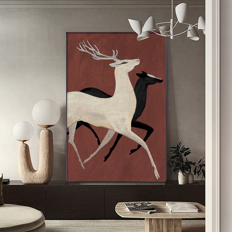 May include: A minimalist art print featuring two stylized deer running against a red background. The deer are white and black, with the white deer in the foreground and the black deer in the background.
