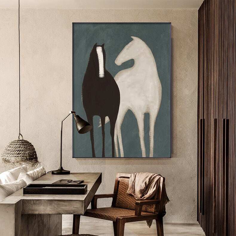 May include: Abstract painting of two horses, one black and one white, standing side by side against a blue background. The painting is framed and hanging on a wall in a room with a wooden floor and a desk.