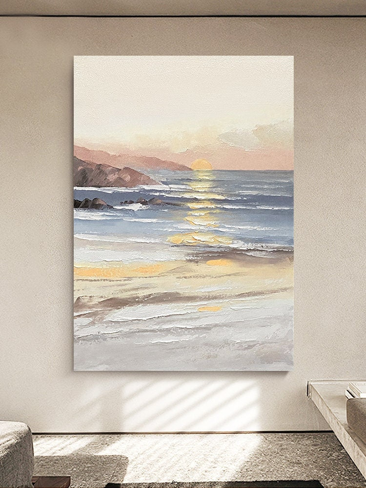 May include: A painting of a seascape with a sunset over the ocean. The sky is a soft pink and orange, and the water is a light blue. The waves are crashing on the shore, and there are some rocks in the foreground.