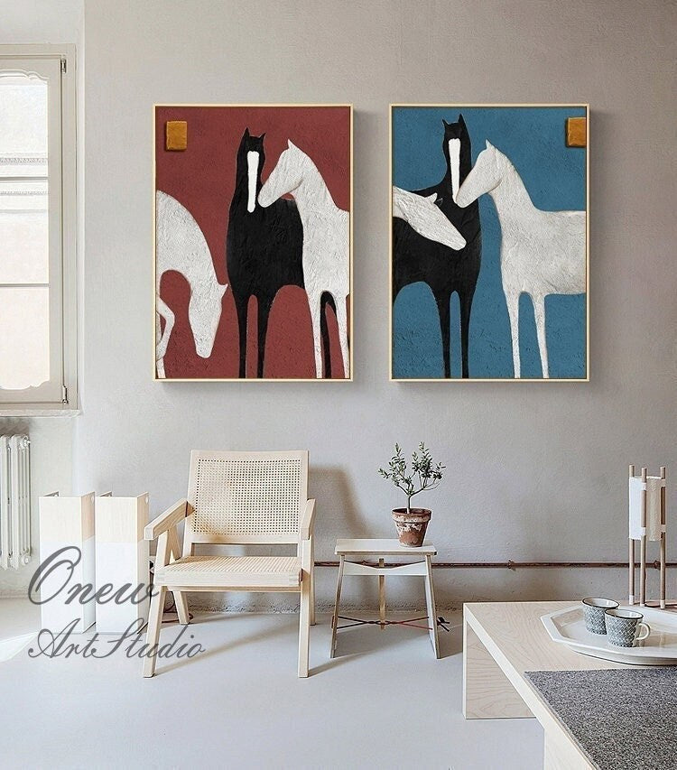 May include: Two abstract paintings of horses in a minimalist style. The painting on the left features three horses in shades of white, black, and brown against a red background. The painting on the right features three horses in shades of white, black, and gray against a blue background.