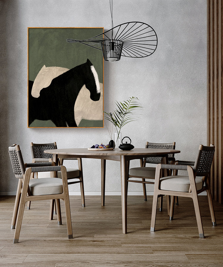 May include: A dining room with a wooden table and chairs. A painting of two horses in black and white on a green background hangs on the wall above the table. A black metal light fixture hangs from the ceiling.