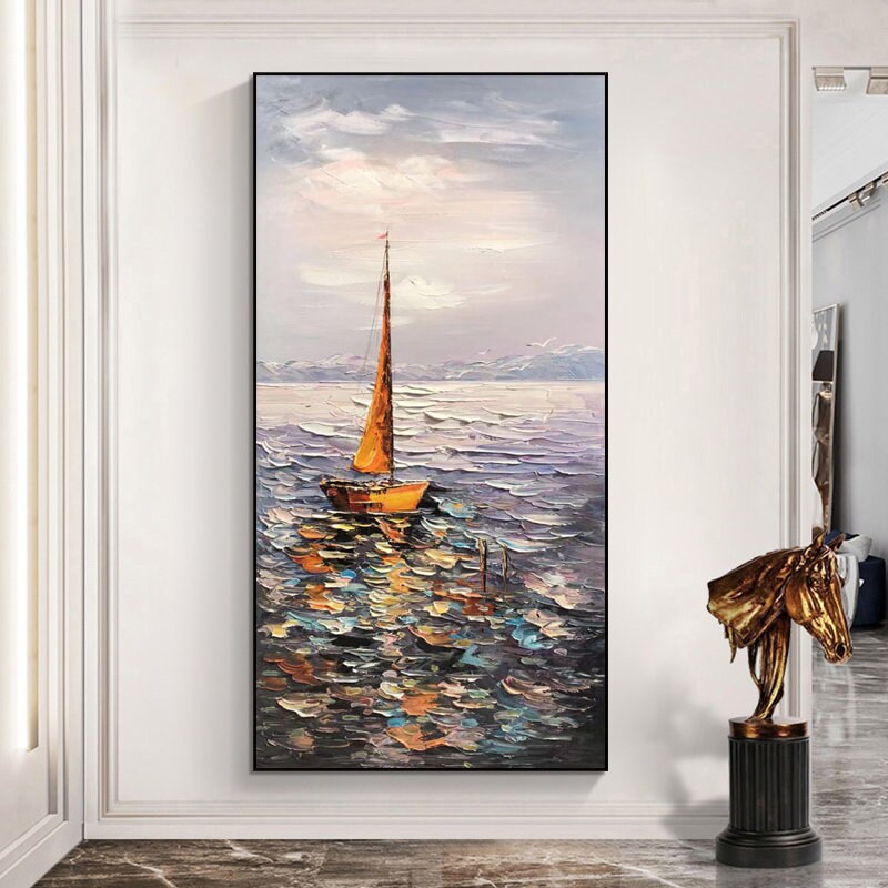 May include: A painting of a sailboat with a yellow sail on a blue and gray sea. The sky is a light blue with white clouds. The painting is in a frame.