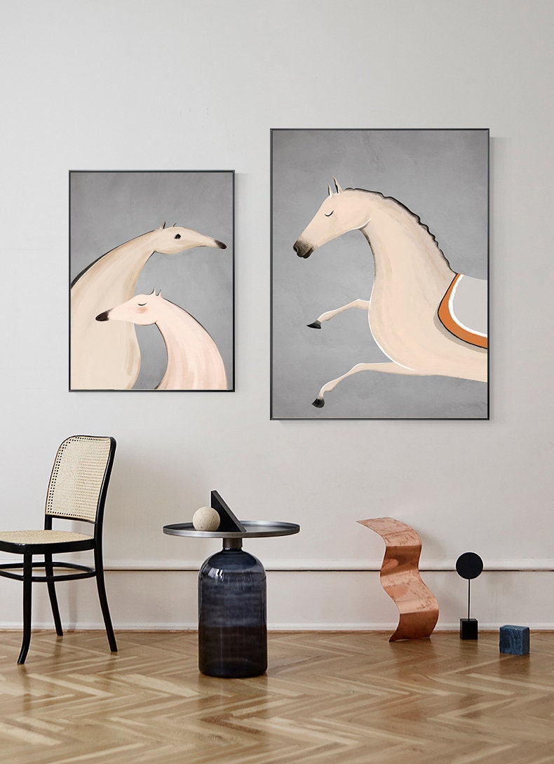 May include: Two framed illustrations of horses. The first illustration shows two horses standing next to each other, one is white and the other is light pink. The second illustration shows a single white horse jumping with its legs in the air. Both illustrations have a gray background.