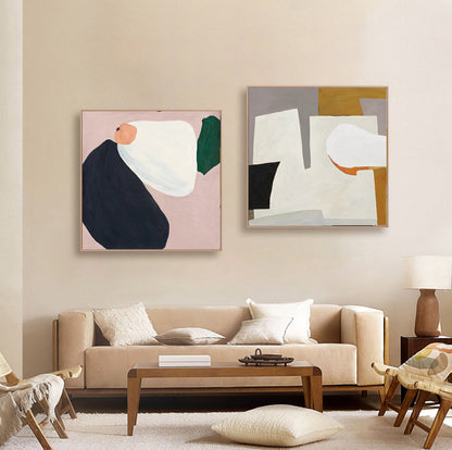 May include: Two abstract paintings with geometric shapes in shades of white, black, green, pink, orange, and brown. The paintings are framed and hung on a beige wall above a beige sofa.