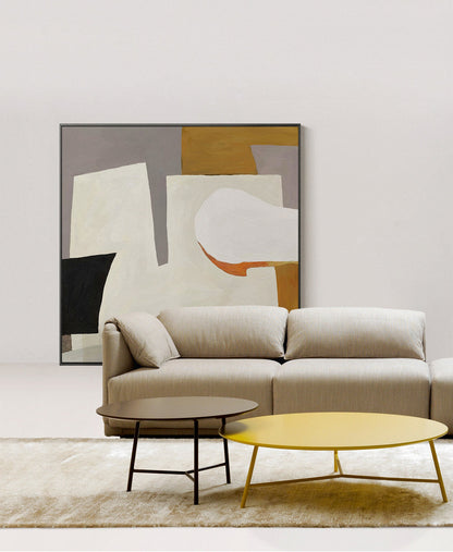 May include: A beige sectional sofa with two coffee tables, one brown and one yellow, in front of a framed abstract painting with white, gray, black, and orange shapes.
