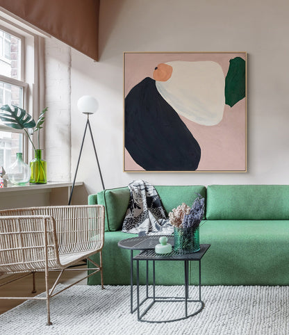 May include: A green sofa with a black and white throw blanket, a wicker chair, and a black metal side table with a green glass vase with dried lavender. A large abstract painting with pink, white, black, and green shapes hangs on the wall above the sofa.