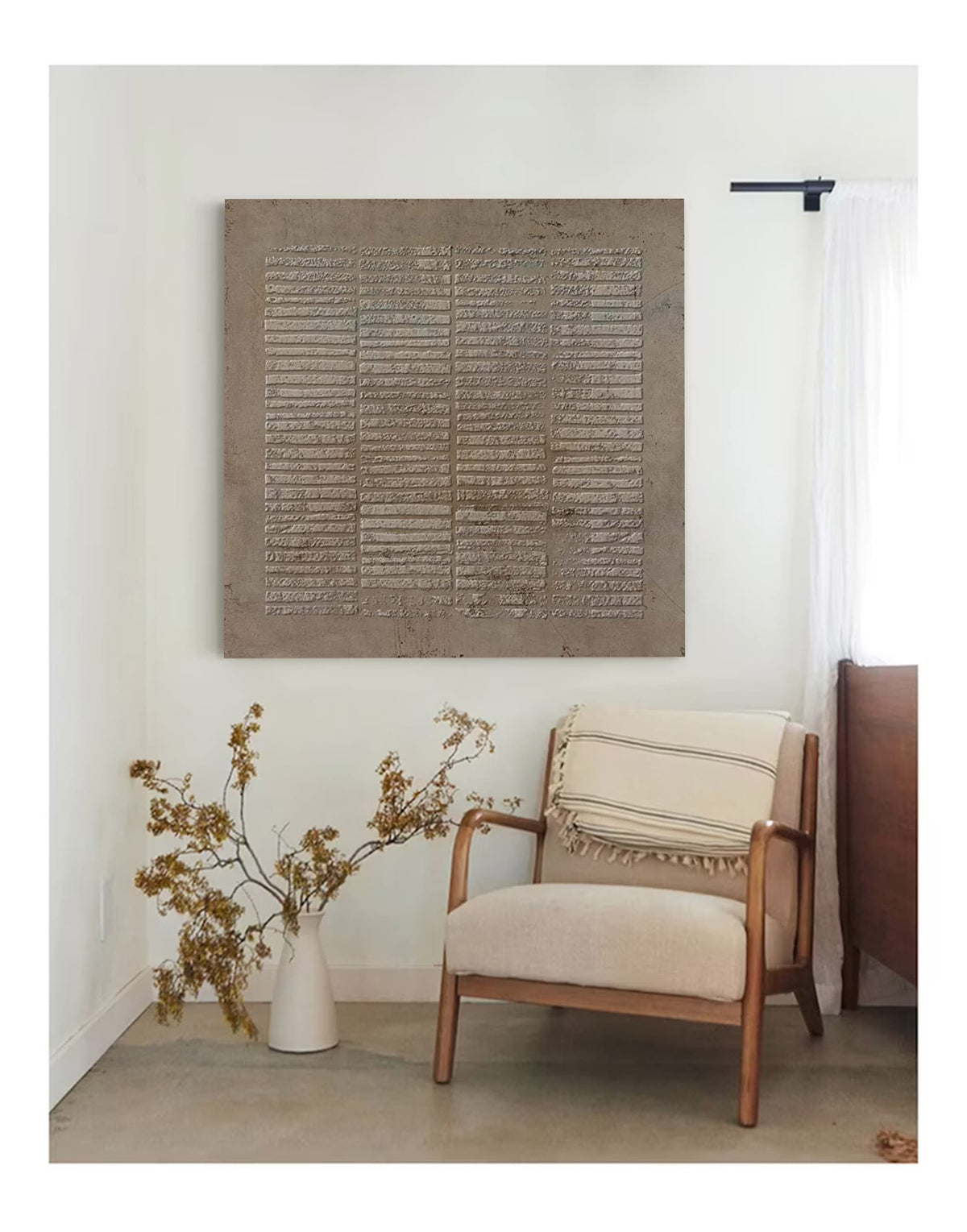 May include: A square wall art piece featuring a textured, taupe-colored surface with a repeating horizontal line pattern. The artwork is mounted on a plain wall above a wooden armchair with a cream-colored cushion and a striped throw blanket.