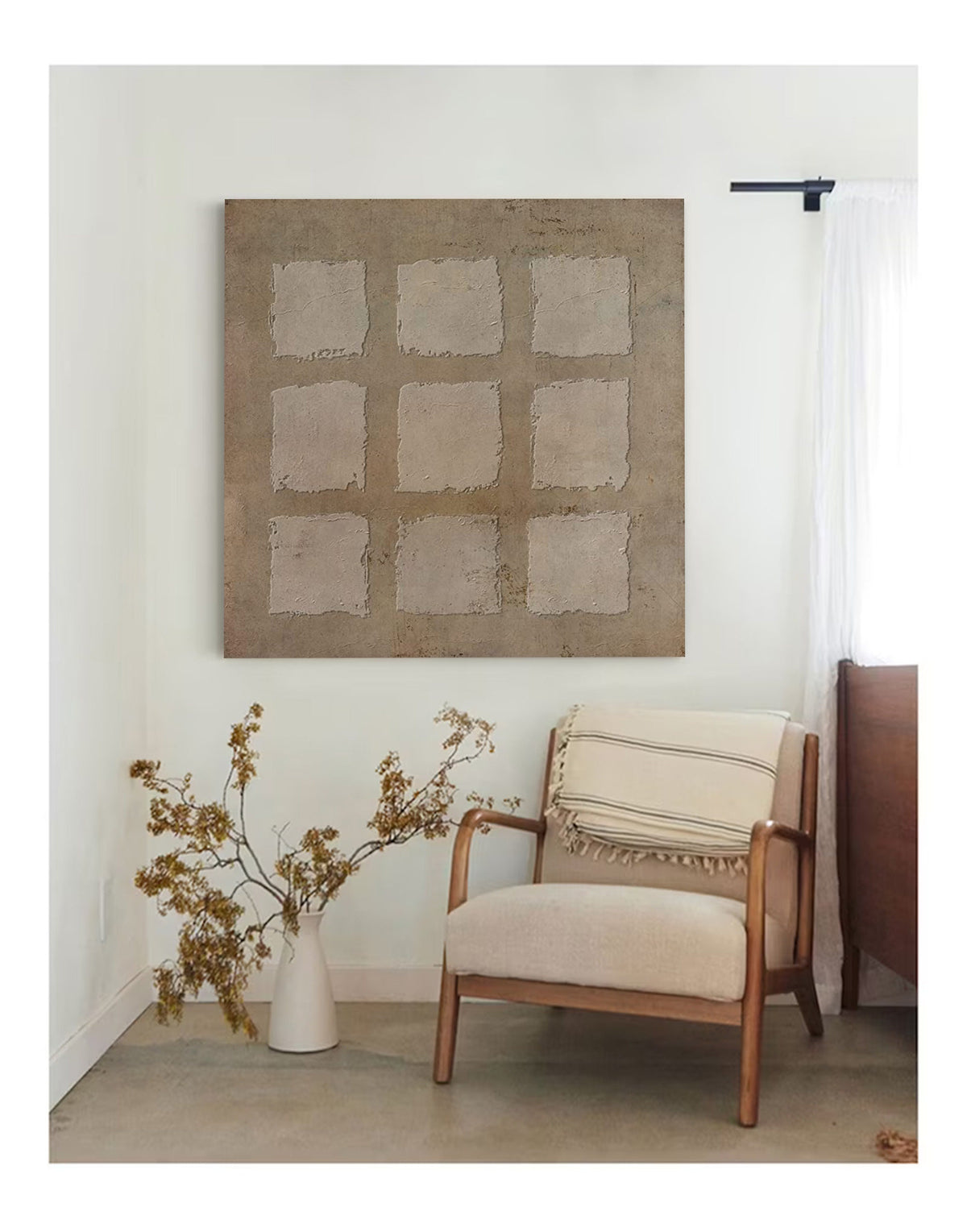 May include: A beige armchair with a white and black striped throw blanket sits in a room with a large abstract painting on the wall. The painting is a light brown color with a grid of squares.