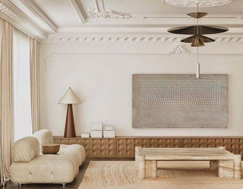 May include: A living room interior featuring a beige tufted sofa, a low wooden sideboard with a textured front, a rectangular stone coffee table, a tall table lamp with a conical shade, and a large rectangular wall art piece with a dotted pattern.