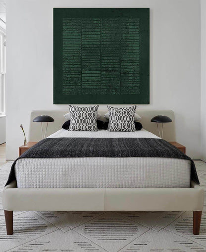 May include: A white bed with a black and white patterned throw blanket and two black and white patterned pillows. A dark green abstract painting hangs above the bed.