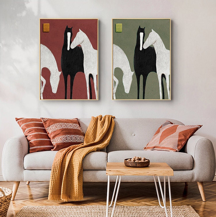 May include: Two framed abstract paintings of three horses in black, white, and grey. The horses are standing close together, with their heads touching. The background of the paintings is a solid color, one red and one green.