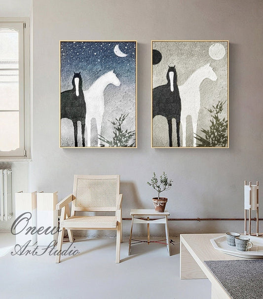 May include: Two abstract paintings of black and white horses with a moon and stars in the background. The paintings are framed in gold and hung on a light gray wall.