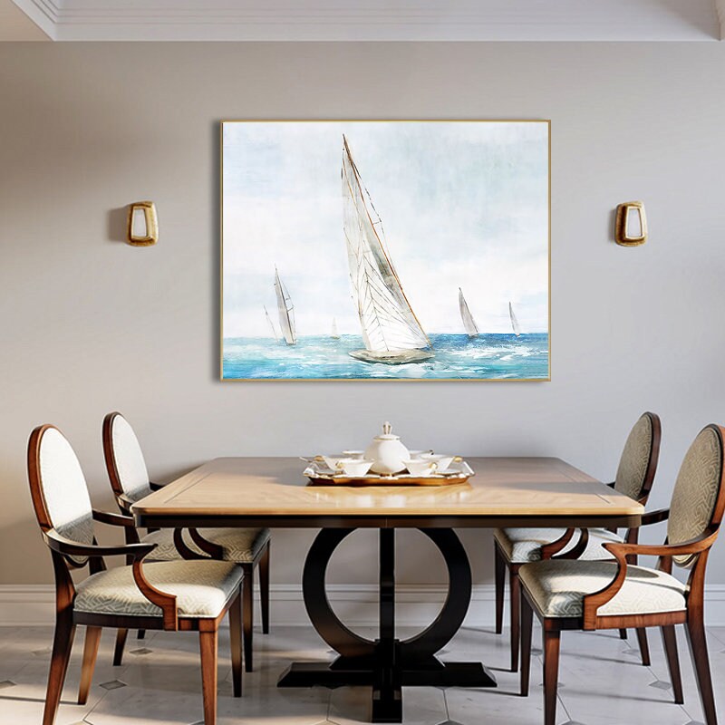 May include: A watercolor painting of sailboats on a blue sea with a light blue sky. The painting is framed in a gold frame and is hanging on a wall in a dining room.
