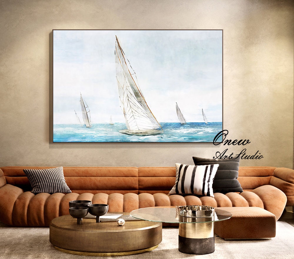 May include: A watercolor painting of sailboats on a blue ocean with a white sky. The painting is framed in a black frame and is hanging on a wall above a brown couch.