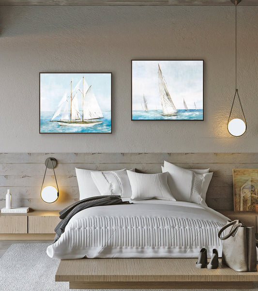 May include: Two framed watercolor paintings of sailboats on the water. The paintings are hung on a light gray wall above a white bed with a gray blanket.