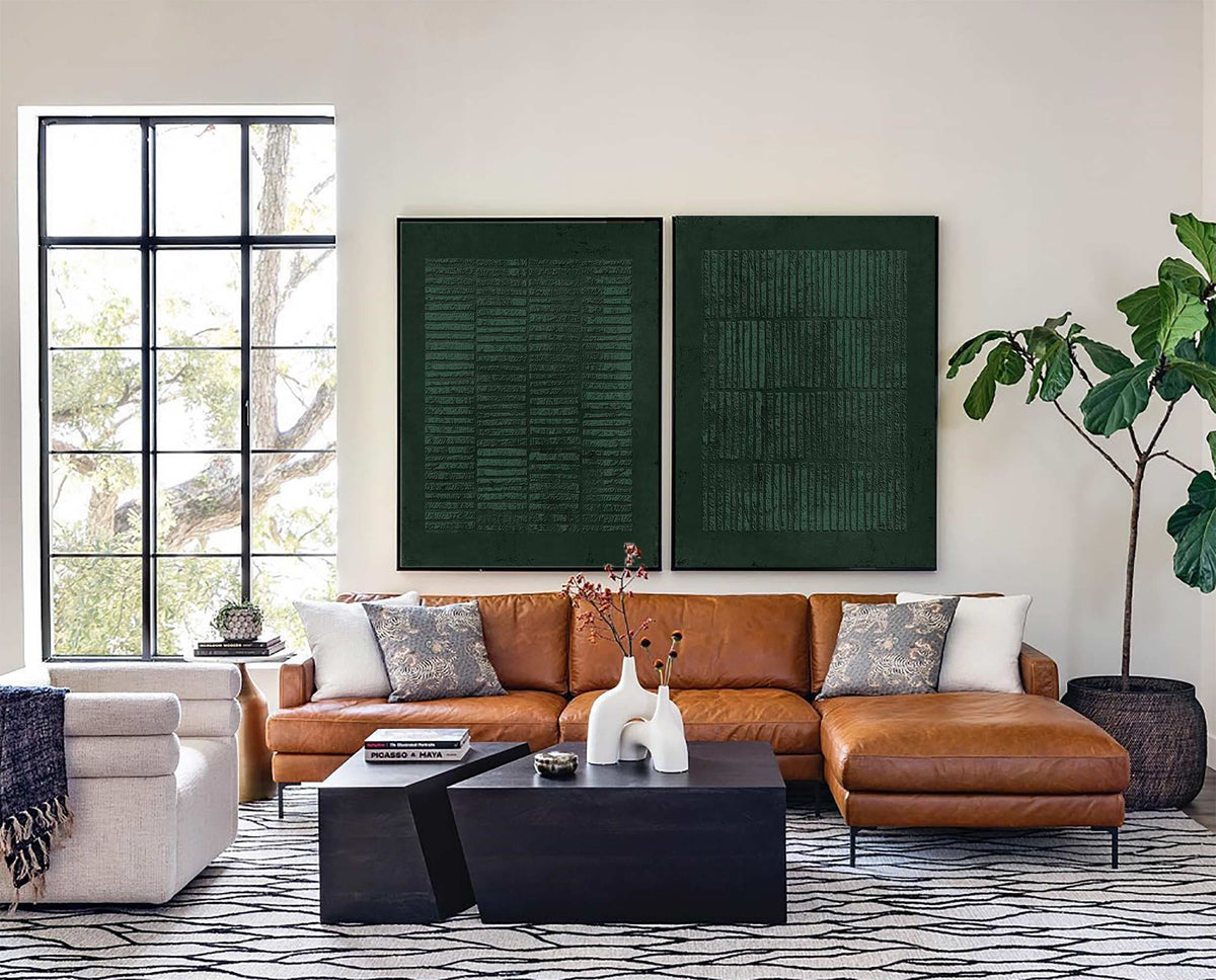 May include: A tan leather sectional sofa with a chaise, two black geometric coffee tables, and two large dark green rectangular wall art pieces with textured linear patterns, positioned in a room with a white patterned rug and a large potted plant.