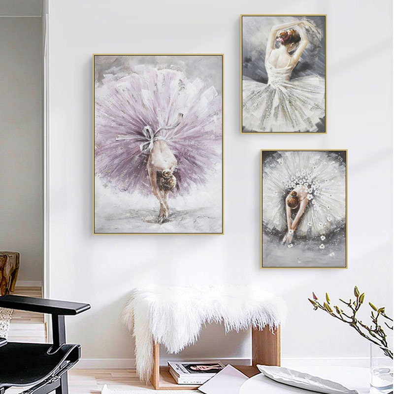 May include: Three framed paintings of ballerinas in various poses. The ballerina in the center is wearing a white tutu and has her arms raised above her head. The ballerina on the left is wearing a purple tutu and is bending over. The ballerina on the right is wearing a white tutu and is looking down at her feet.