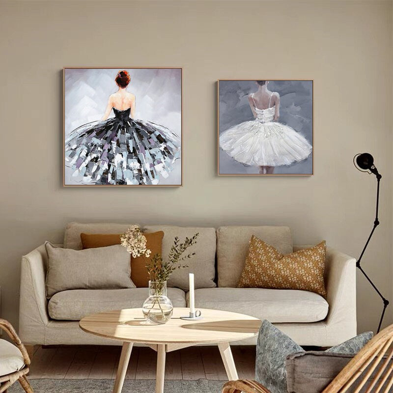 May include: Two framed paintings of ballerinas wearing tutus. The ballerina on the left is wearing a black tutu and the ballerina on the right is wearing a white tutu. Both ballerinas are facing away from the viewer.
