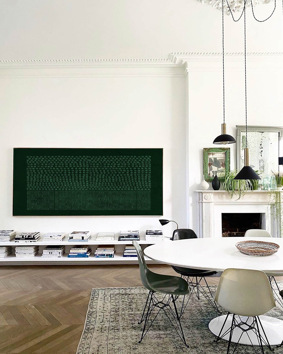 May include: A large rectangular wall art piece featuring a deep forest green background with a pattern of small, light green circular dots on the top half and vertical lines on the bottom half, displayed in a white room above a low white shelf.