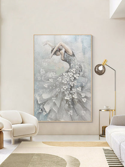 May include: An abstract painting of a dancer in a flowing gown. The artwork features a woman in a silver dress adorned with white floral accents. The background is a soft blend of gray and blue hues, framed in a light wood.