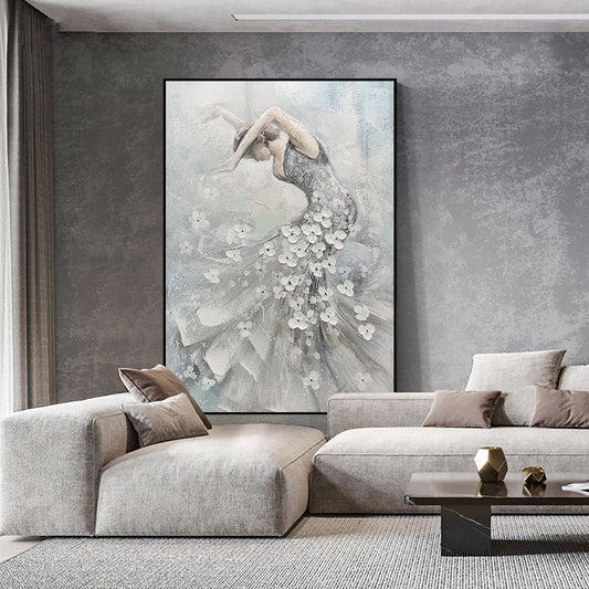 May include: Abstract painting of a ballerina in a flowing gown, adorned with white floral accents. The artwork features a palette of gray, white, and light blue, set against a neutral background. The painting is framed in black and displayed in a modern living space.