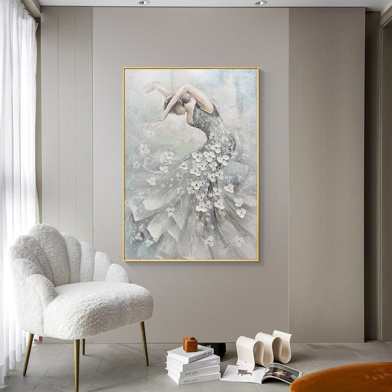 May include: A framed painting of a ballerina in a flowing gray dress adorned with white floral accents. The artwork features a gold frame and a soft, textured background, creating a sense of movement and grace.