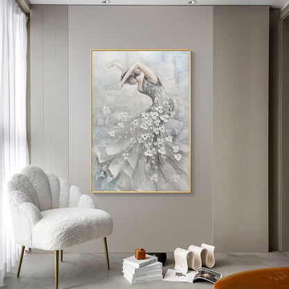 May include: A framed painting of a ballerina in a flowing gray dress adorned with white floral accents. The artwork features a gold frame and a soft, textured background, creating a sense of movement and grace.