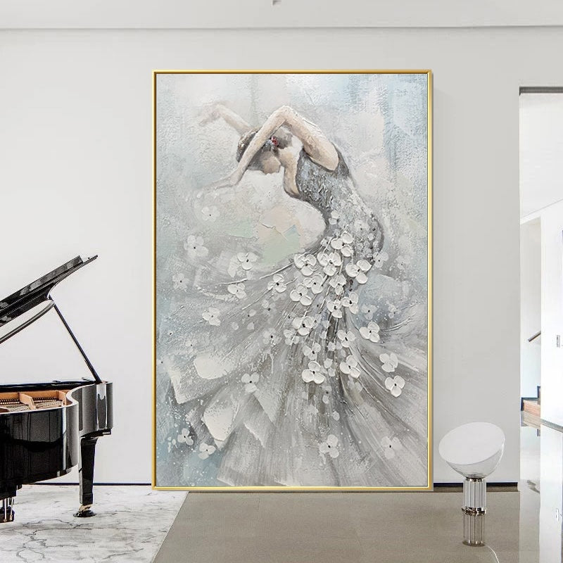May include: An abstract painting of a dancer in a flowing gown, adorned with white floral accents. The artwork features a palette of gray, white, and light blue, framed in gold. The dancer's pose is graceful, with arms extended.