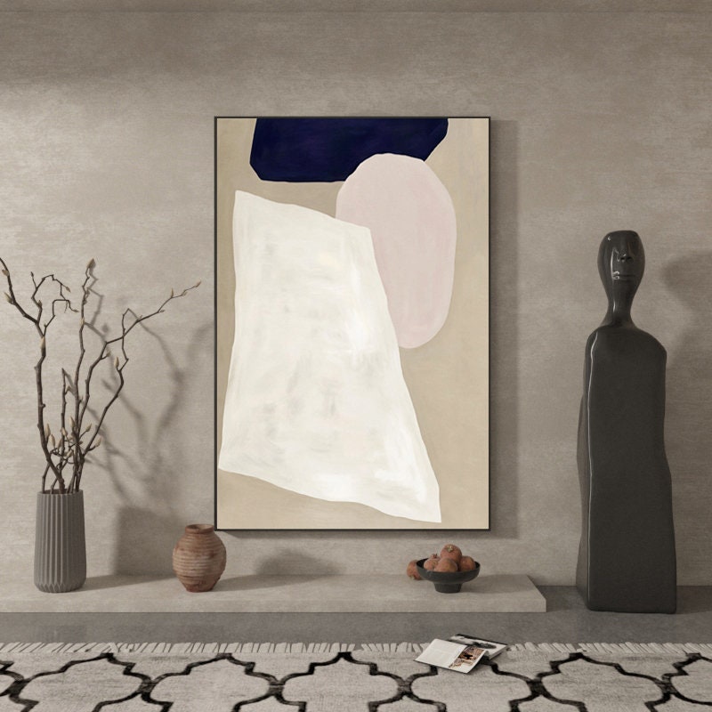 May include: Abstract art print with a white, pink, and blue geometric design on a beige background. The print is framed in black and is hanging on a wall.