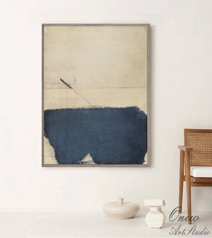 May include: Abstract art painting with a beige background and a dark blue brushstroke across the bottom. The painting is framed in a light wood frame.