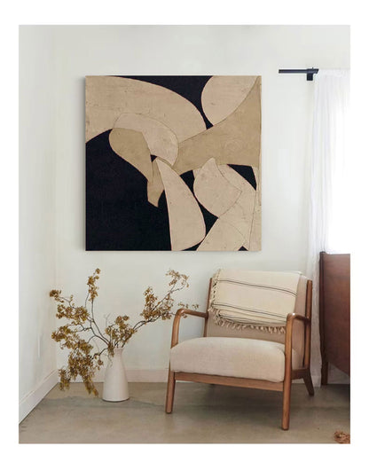 May include: An abstract painting with beige and black shapes hangs above a mid-century modern chair with a cream-colored cushion. A white vase holds dried branches, and a striped throw blanket rests on the chair.