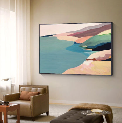 May include: Abstract landscape painting with a coastal scene. The painting features a blue body of water, a sandy beach, and colorful hills in shades of pink, green, and brown.