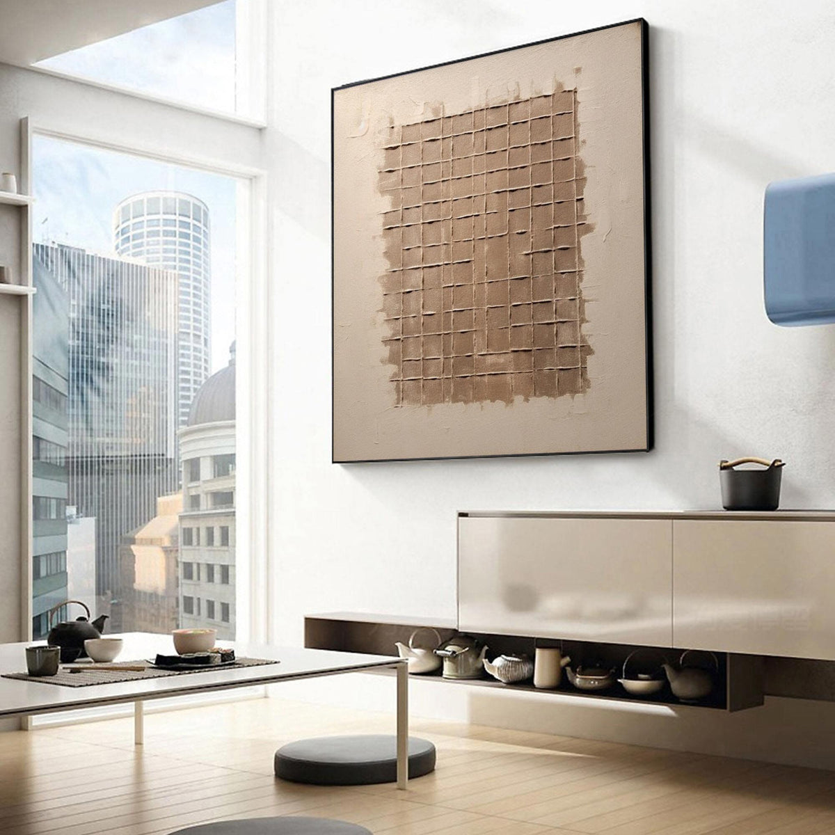May include: A square abstract painting with a brown grid pattern on a beige background. The painting is hanging on a white wall in a modern living room with a table and chairs.