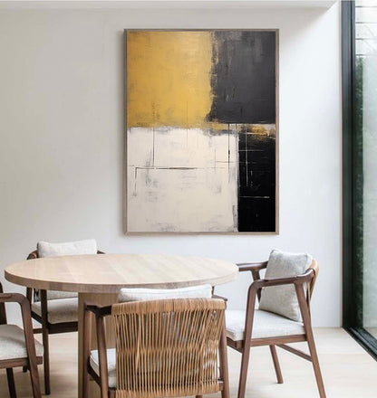 May include: Abstract painting with geometric shapes in shades of gold, black, and white. The painting is framed and hanging on a wall in a dining room.