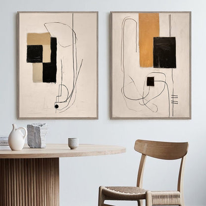 May include: Two abstract paintings with black, white, and beige geometric shapes and lines on a cream background. The paintings are framed in a light wood frame and are hanging on a white wall.