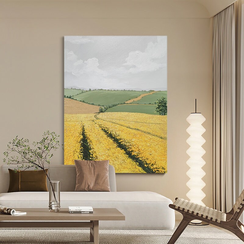 May include: A painting of a landscape with rolling green hills and a field of yellow wildflowers. The sky is cloudy and there is a path leading through the field.
