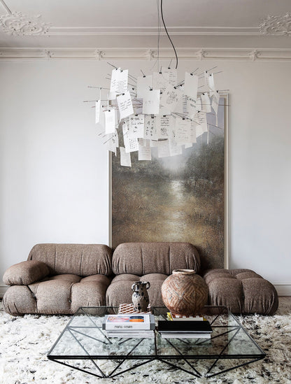 May include: A brown sectional sofa with a glass coffee table in front of it. The coffee table has a black metal frame and is decorated with books and a ceramic vase. A large abstract painting hangs on the wall behind the sofa.