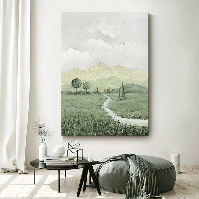May include: A painting of a green landscape with a winding path leading to a mountain range in the distance. The sky is a light gray with white clouds. The painting is done in a muted color palette.