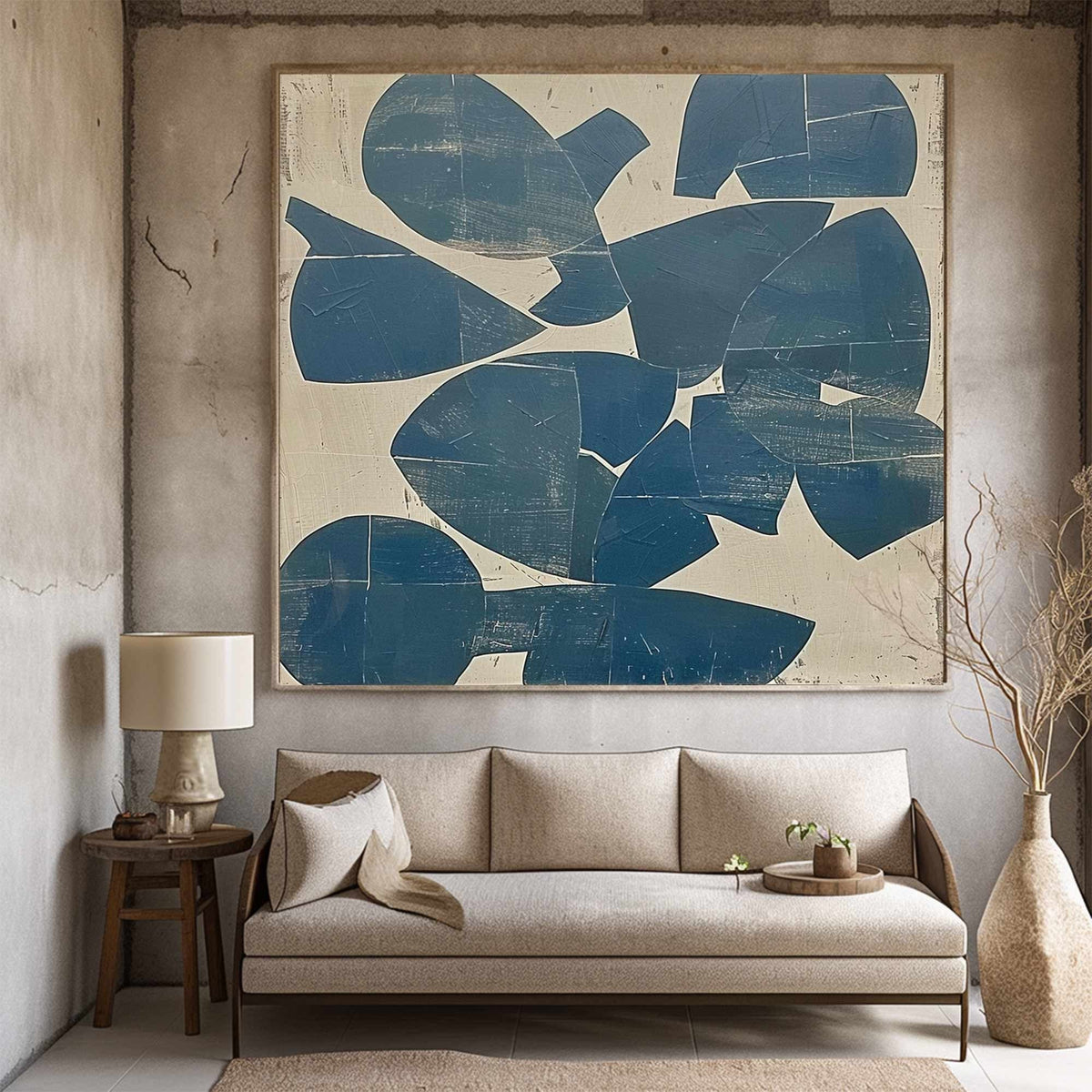 May include: Large abstract painting with a cream background and overlapping blue shapes. The artwork hangs above a beige sofa with a wooden frame. A small wooden side table with a lamp and a vase with dried branches complete the room's decor.