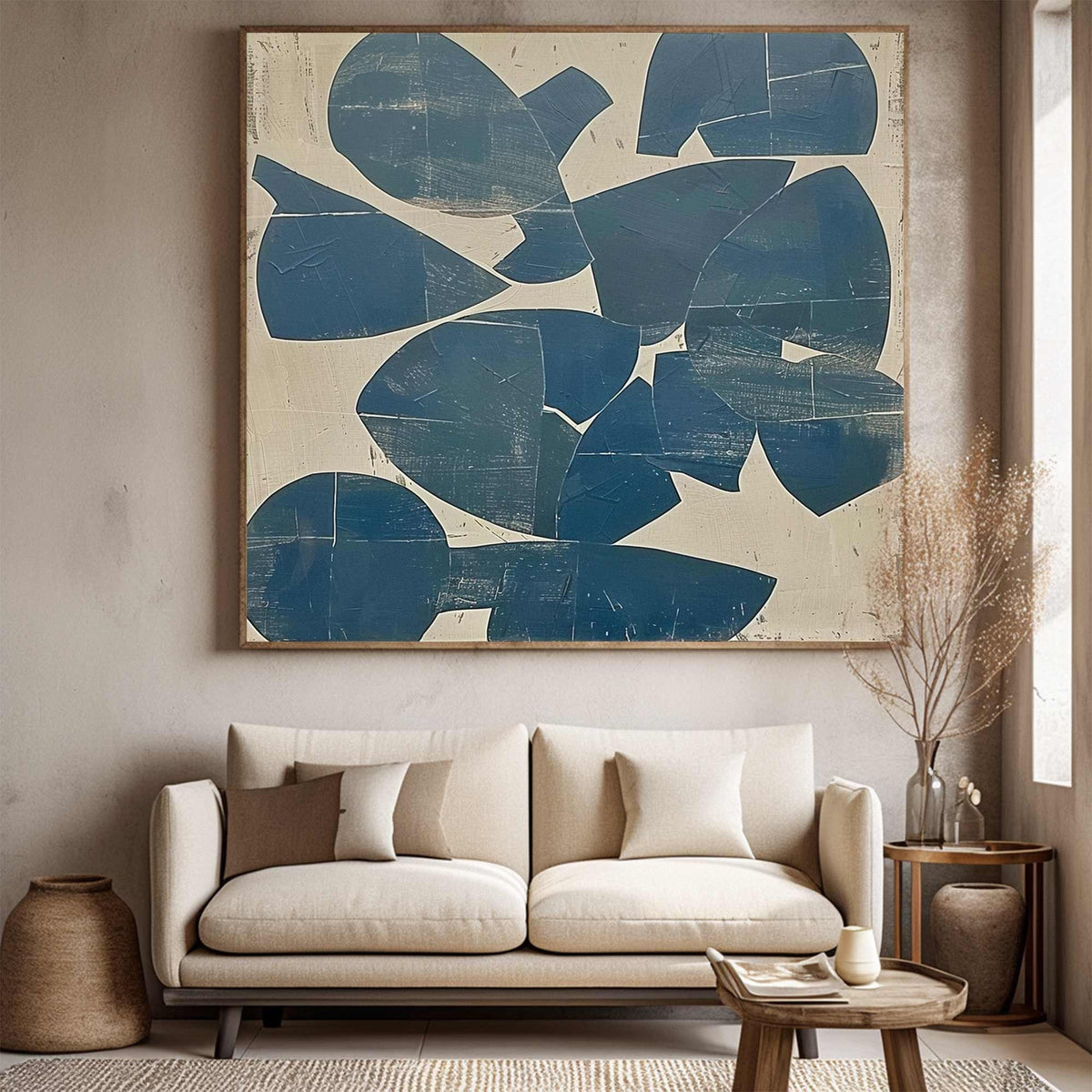 May include: Large abstract painting with a wooden frame. The artwork features overlapping blue shapes on a beige background. The painting hangs above a beige sofa with decorative pillows, creating a modern living room aesthetic.
