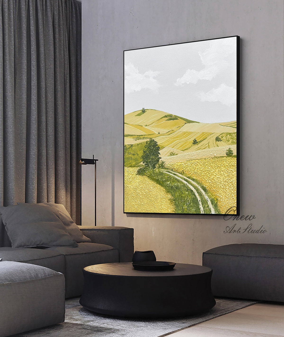 May include: A painting of a landscape with rolling hills and a dirt road winding through a field of yellow wildflowers. The sky is a light blue with white clouds. The painting is framed in black.