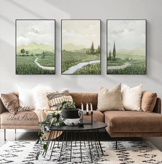 May include: Three framed landscape paintings with a green and white color scheme. The paintings depict a winding path through a grassy field with trees and mountains in the background.