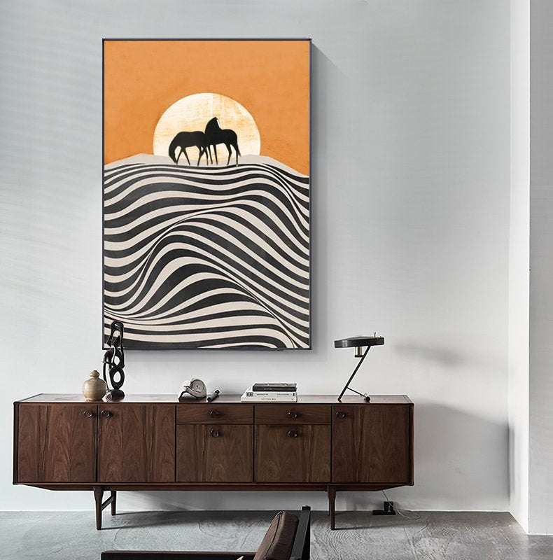 May include: Abstract art print featuring two black silhouettes of horses standing on a hill with a large orange sun behind them. The hill is made up of black and white wavy lines.