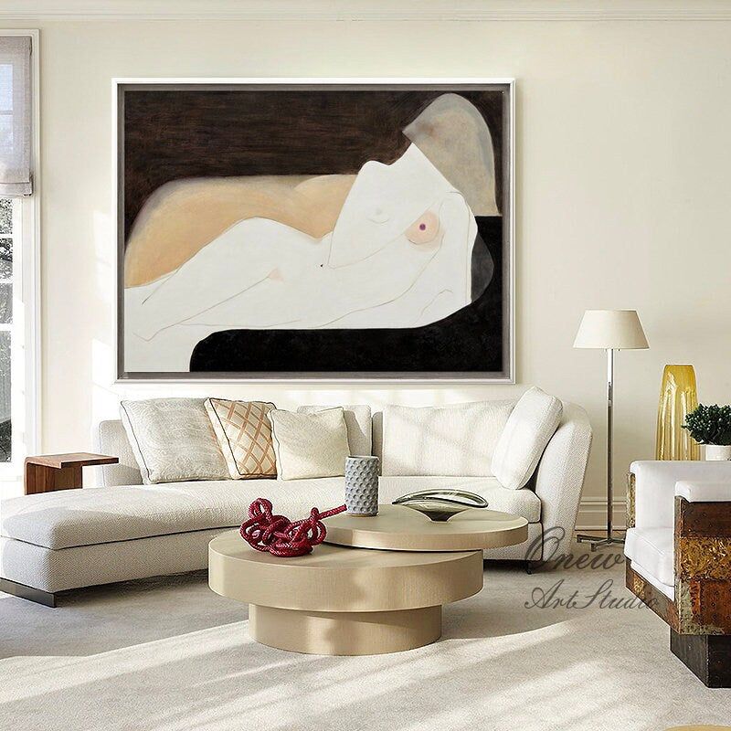 May include: Abstract painting of a nude figure lying down on a black background. The figure is painted in shades of white, pink, and beige. The painting is framed in a white frame and is hanging on a white wall.