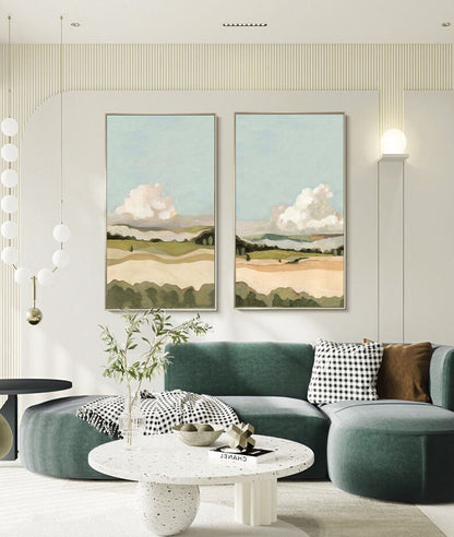 May include: Two framed landscape paintings with a green, brown, and blue color scheme. The paintings depict a field with rolling hills and fluffy white clouds in the sky.
