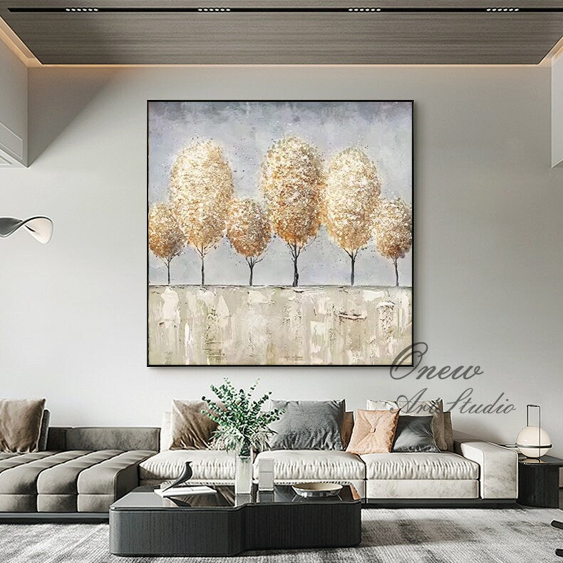 May include: Abstract painting of a row of five trees with gold and brown foliage on a light gray background. The trees are painted in a textured style with visible brushstrokes. The painting is framed in black.