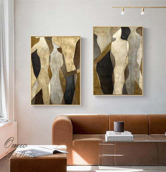 May include: Two abstract paintings with gold frames, featuring geometric shapes in shades of brown, beige, and black. The paintings depict stylized figures with a minimalist aesthetic.